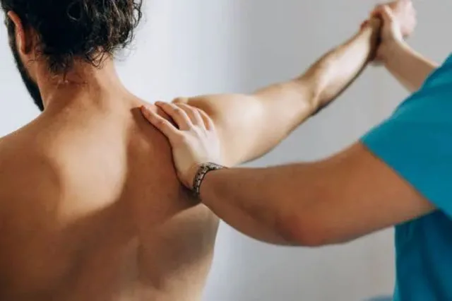 A physiotherapist stretching and assessing shoulder movement